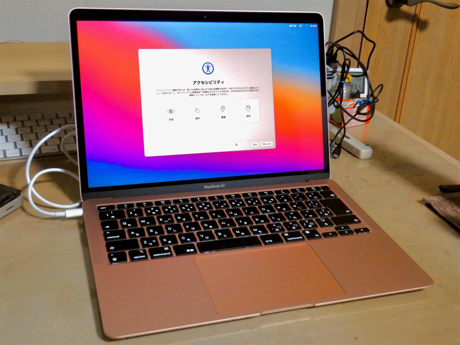 MacBook Air doré à puce M1 posé sur un bureau, écran affichant l'étape Accessibilité de la configuration de macOS