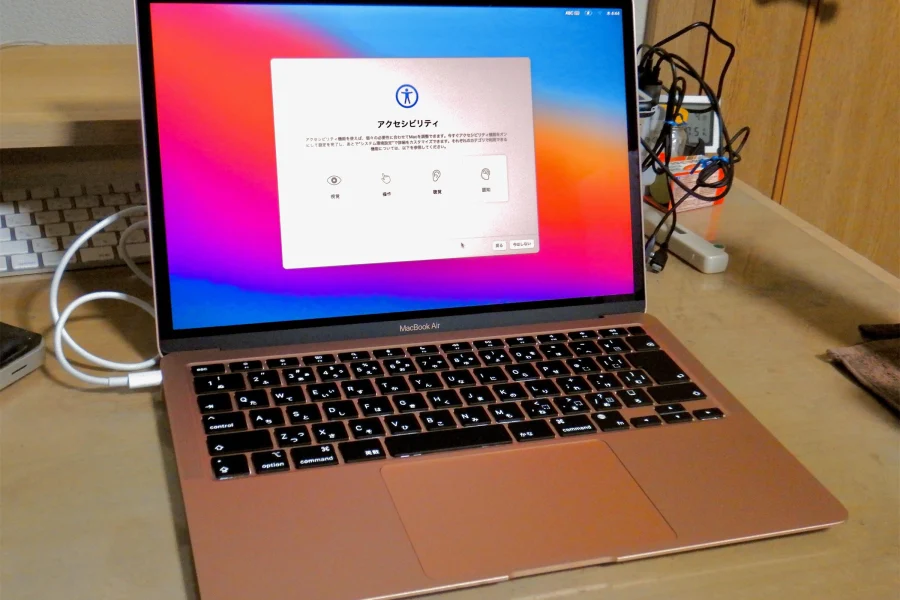 MacBook Air doré à puce M1 posé sur un bureau, écran affichant l'étape Accessibilité de la configuration de macOS
