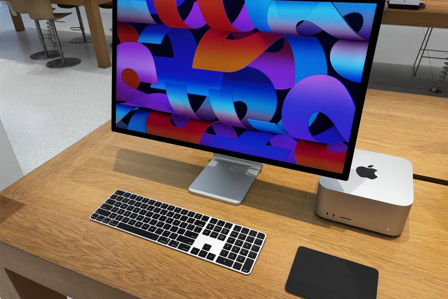 Mac Studio, écran Studio Display, clavier et trackpad noirs posés sur une table en bois