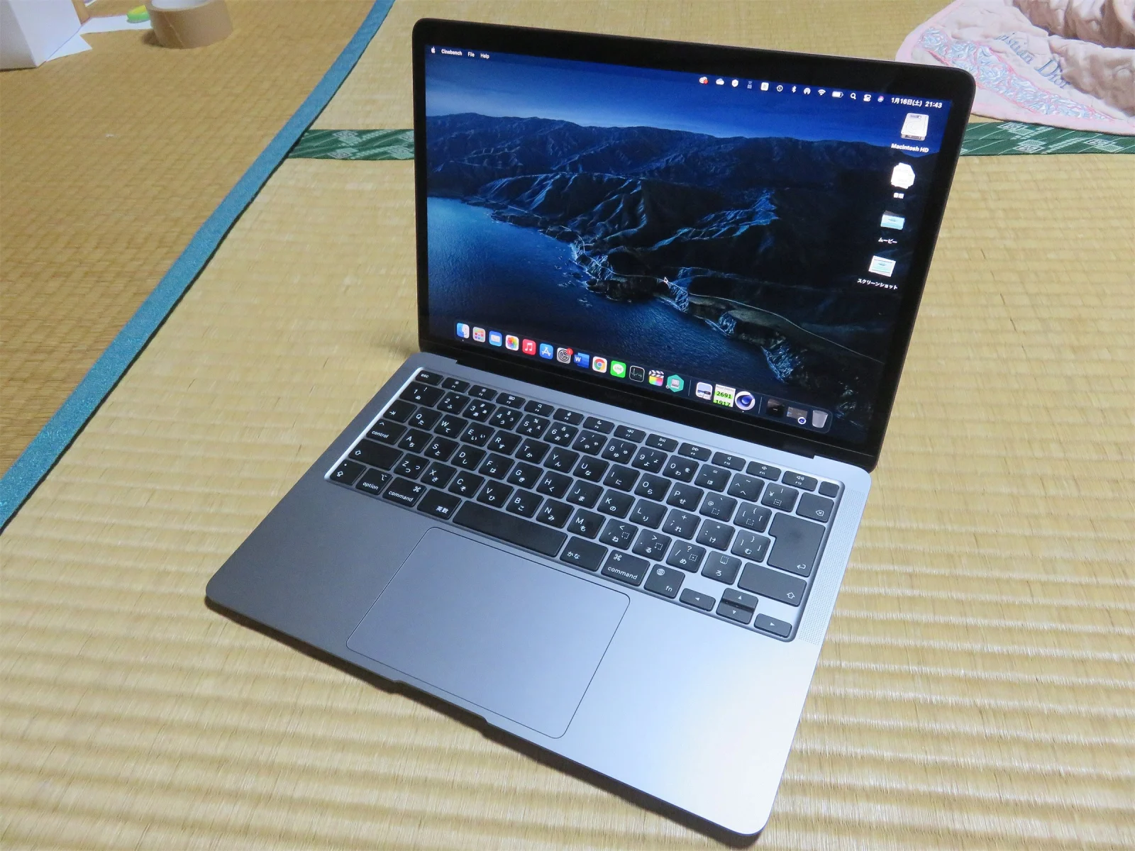 MacBook Air gris sidéral ouvert sur un tatami, des icônes de fichiers alignées sur le bord droit du bureau