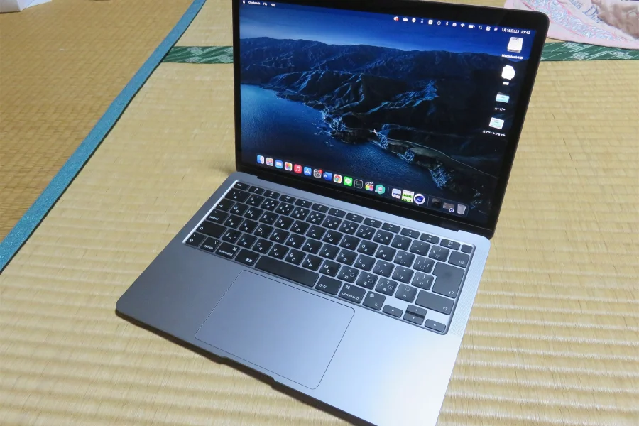 MacBook Air gris sidéral ouvert sur un tatami, des icônes de fichiers alignées sur le bord droit du bureau